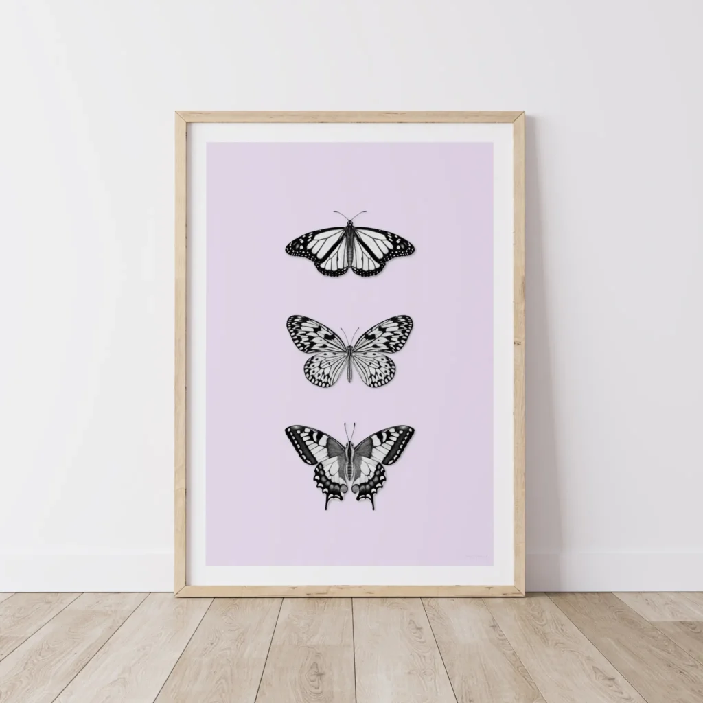Framed art print with three black butterflies on timber floor.