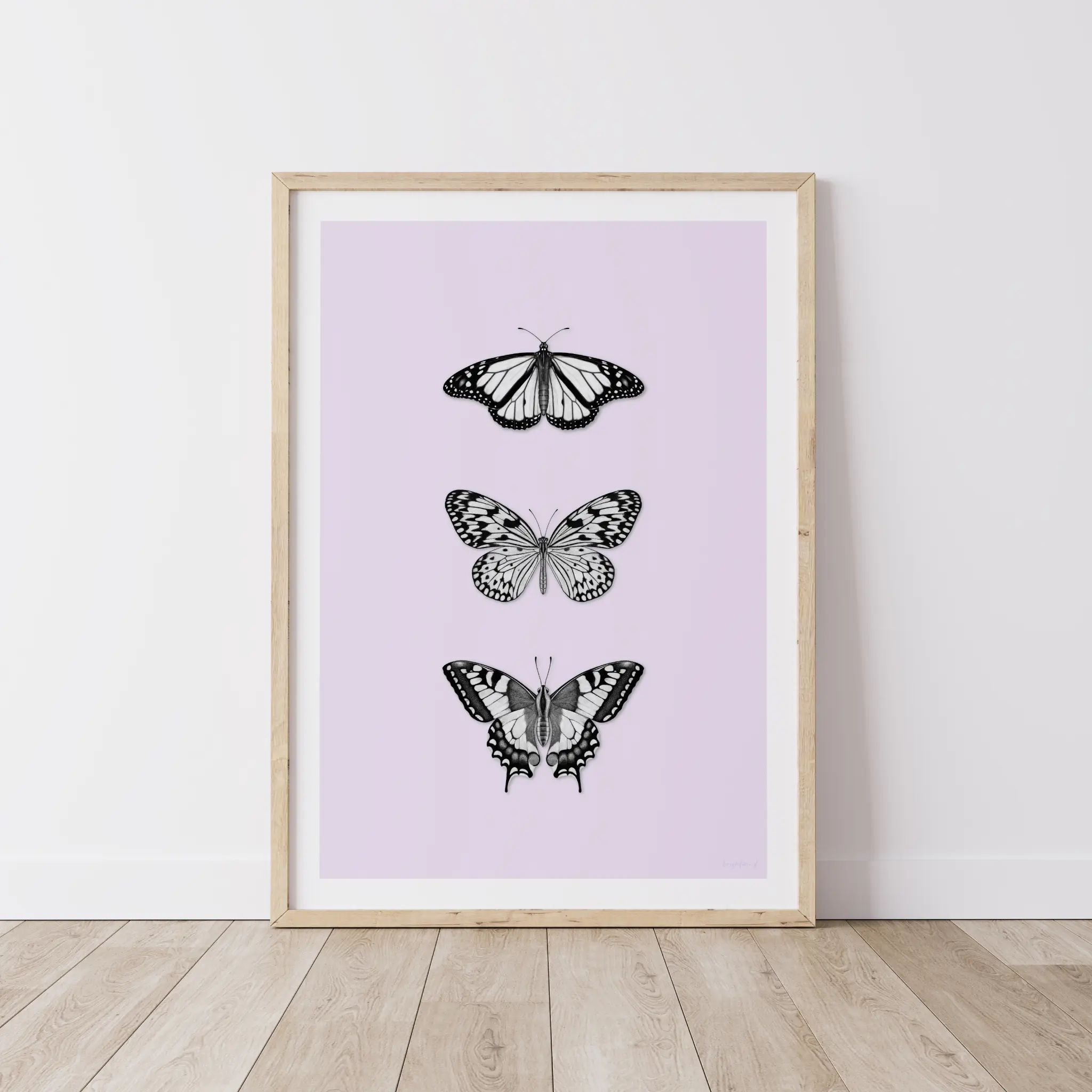 Framed art print with three black butterflies on timber floor.