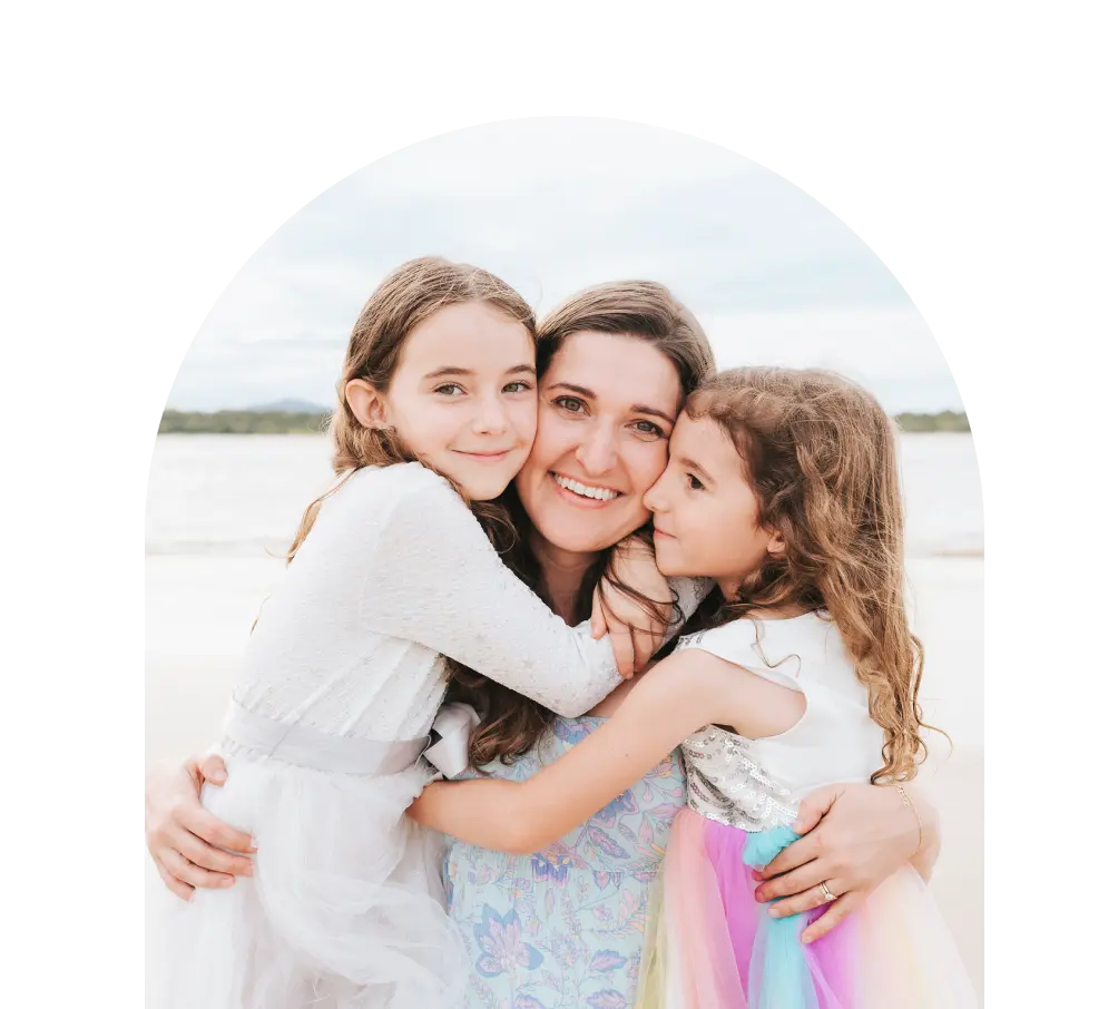 Jacqui hugging her two daughters on beach.