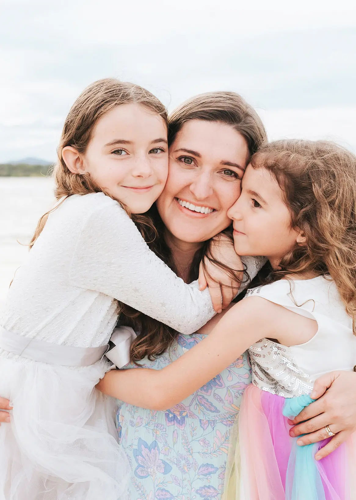 Jacqui hugging her two daughters on beach.